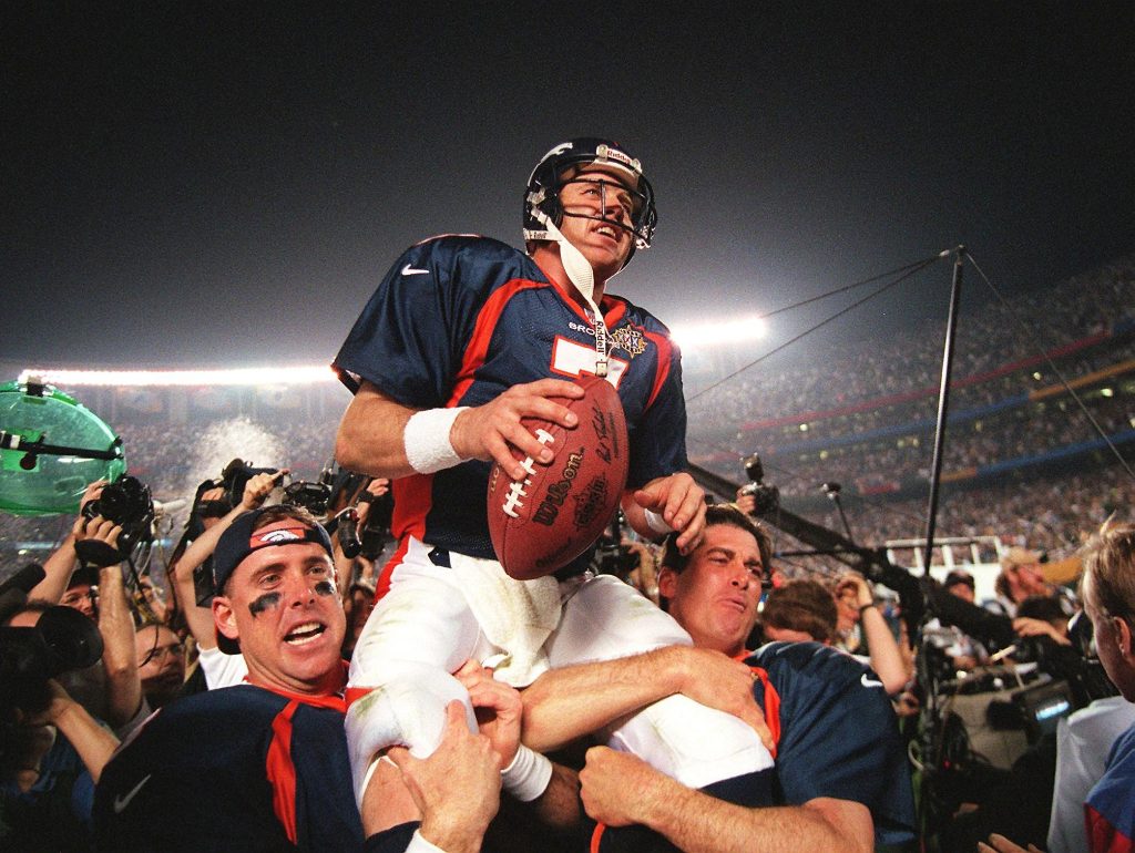 Denver Broncos quarterback John Elway (C) is carri