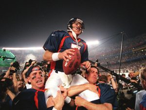 Denver Broncos quarterback John Elway (C) is carri